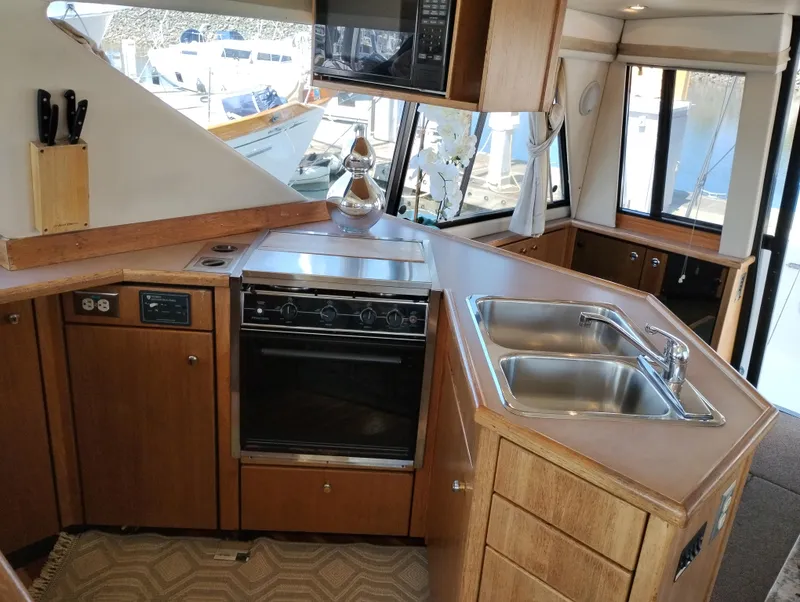 Slide: The Image of 1997 Bayliner 3988 Motor Yacht kitchen with stove, sink, and wooden cabinetry. - 18