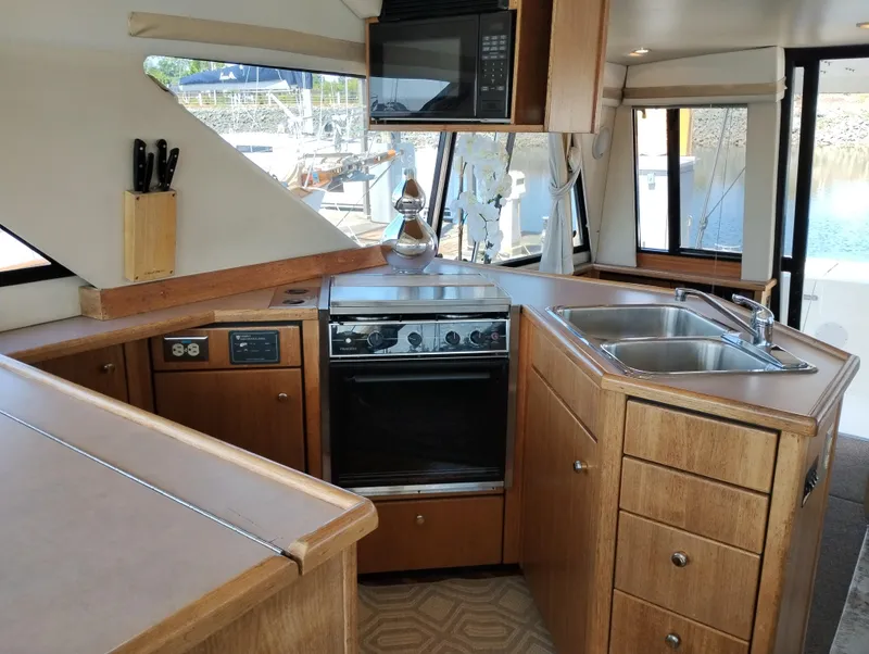 Slide: The Image of 1997 Bayliner 3988 Motor Yacht kitchen with wooden cabinetry, stove, sink, and microwave. - 19