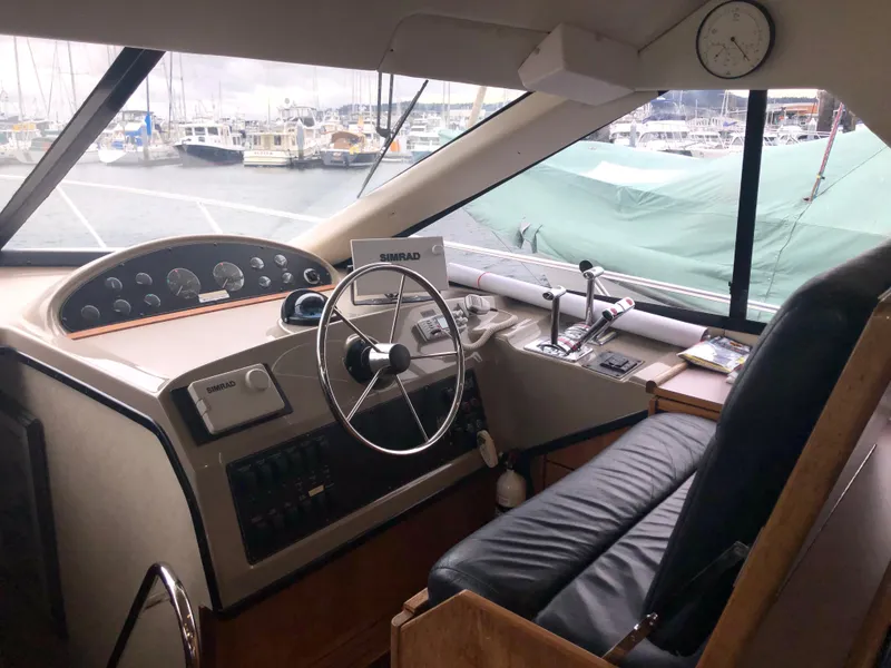 Slide: The Image of 1997 Bayliner 3988 Motor Yacht helm with steering wheel, controls, and marina view. - 24