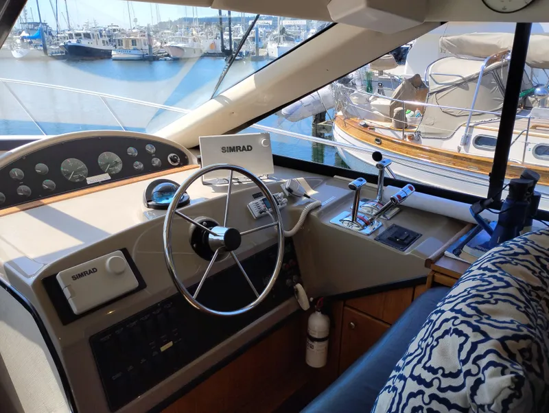 Slide: The Image of 1997 Bayliner 3988 Motor Yacht helm with steering wheel, controls, and marina view. - 26