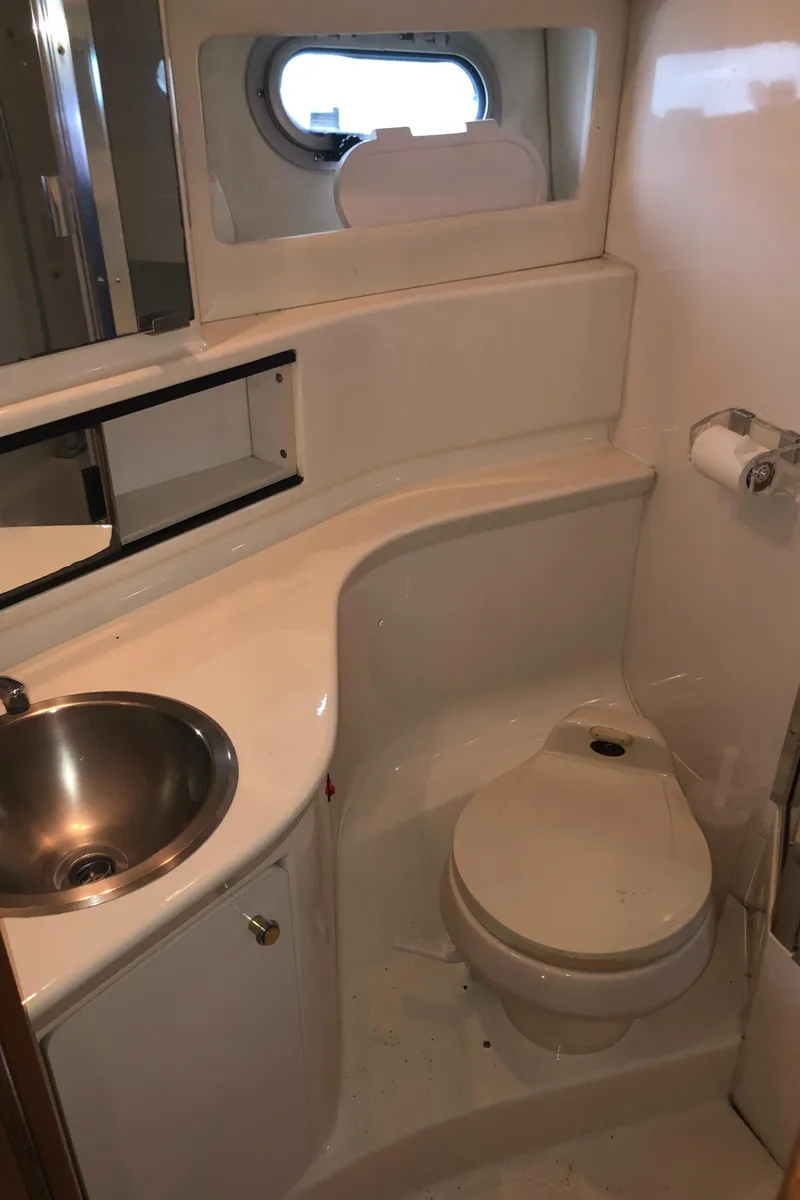 Slide: The Image of Compact bathroom in 1997 Bayliner 3988 Motor Yacht with sink, toilet, and porthole window. - 35