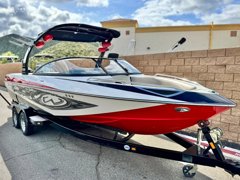 Slide: The Image of 2007 Malibu Wakesetter 247 LSV boat on trailer, red and white design, parked outdoors. - 1