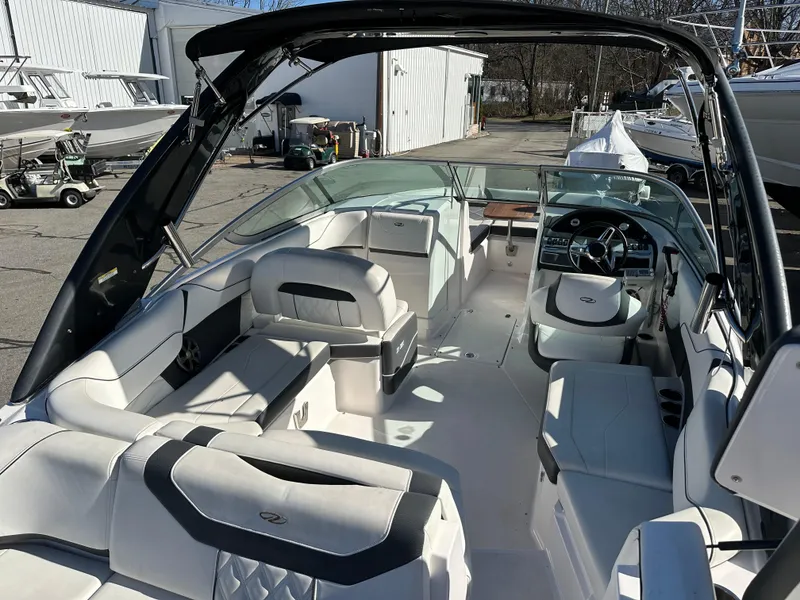 Slide: The Image of 2018 Regal 23 OBX boat interior with seating and steering wheel in a marina setting. - 9