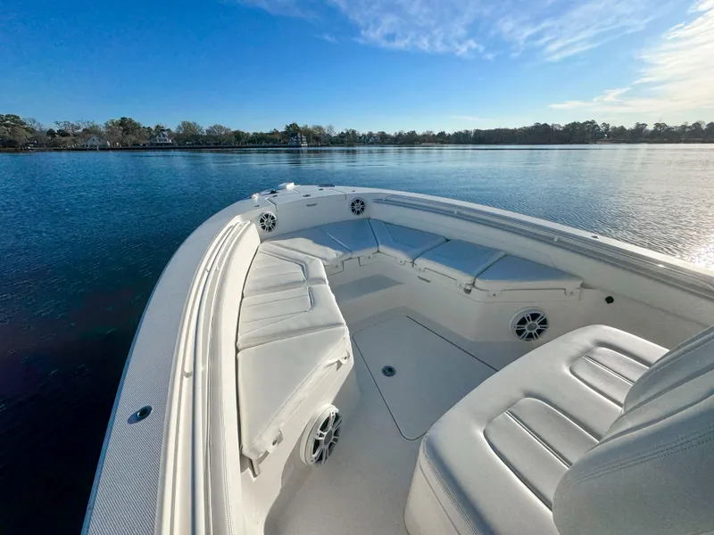 Slide: The Image of 2022 Regulator 24 XO boat interior with cushioned seating on calm water. - 10