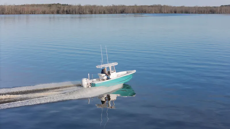 Slide: The Image of 2022 Regulator 24 XO boat cruising on calm water, surrounded by serene landscape. - 2