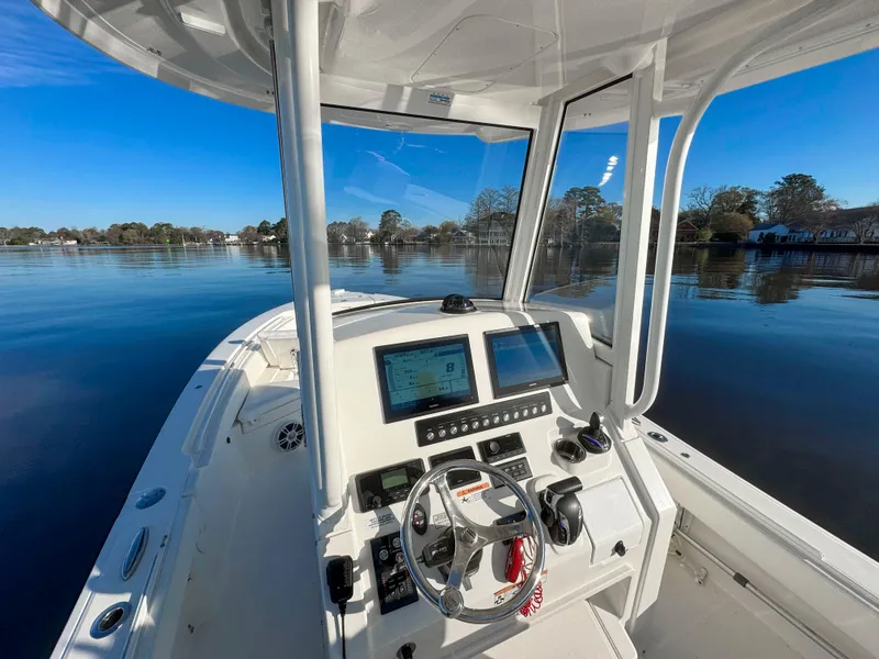 Slide: The Image of 2022 Regulator 24 XO boat cockpit with modern controls on a calm lake. - 21