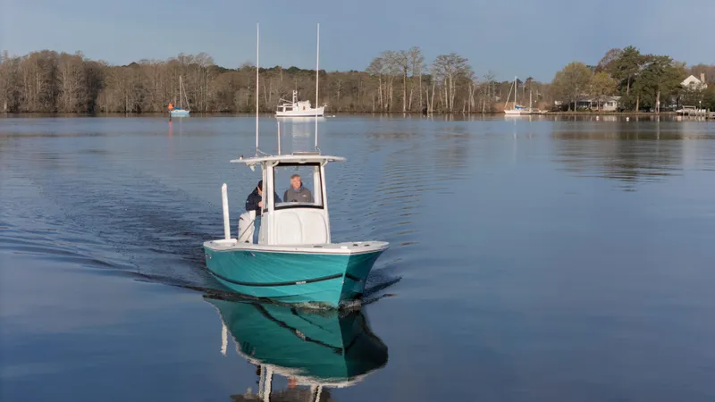 Slide: The Image of 2022 Regulator 24 XO boat cruising on a calm lake with trees in the background. - 27