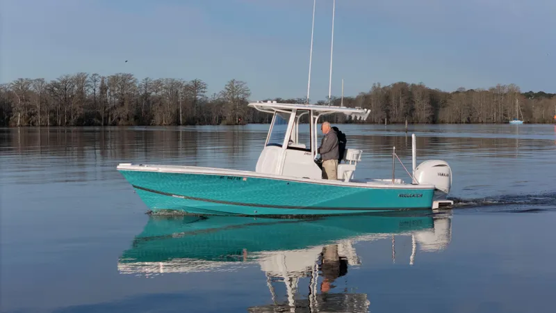 Slide: The Image of 2022 Regulator 24 XO boat cruising on calm water with trees in the background. - 28