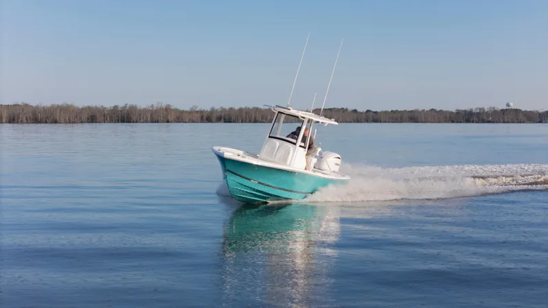 Slide: The Image of 2022 Regulator 24 XO boat cruising on calm water under clear blue sky. - 33