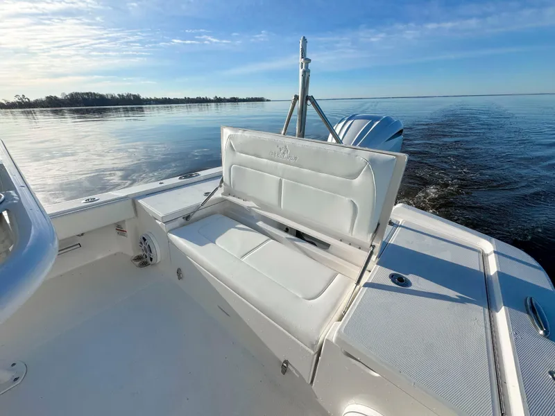 Slide: The Image of 2022 Regulator 24 XO boat with white seating, cruising on calm waters under a clear sky. - 5