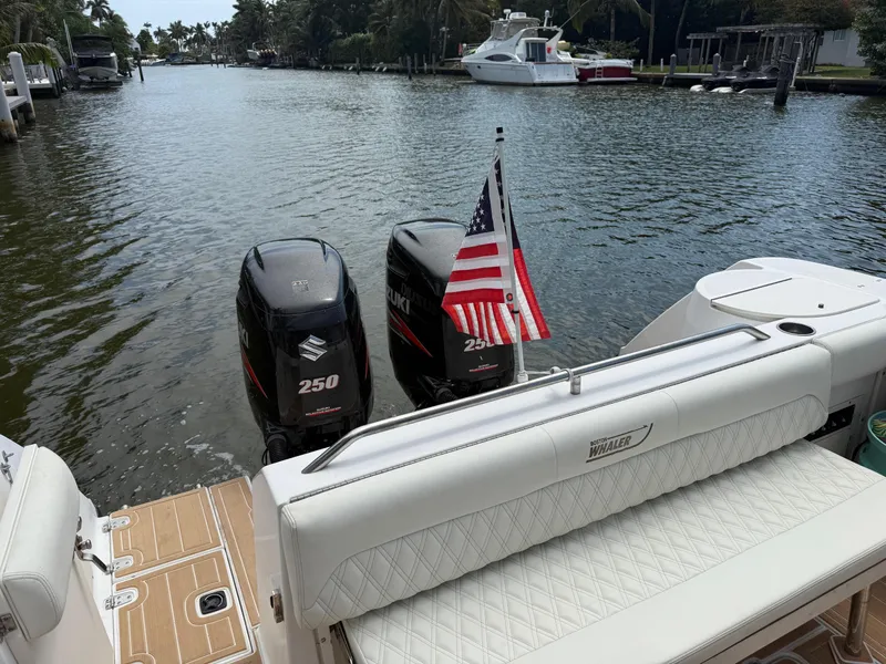 Slide: The Image of Boston Whaler 28 Conquest 1999 with twin Suzuki engines and American flag on a calm waterway. - 16