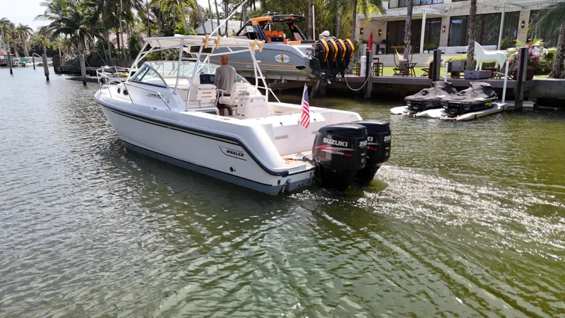 Slide: The Image of 1999 Boston Whaler 28 Conquest boat cruising on a sunny canal with palm trees. - 19