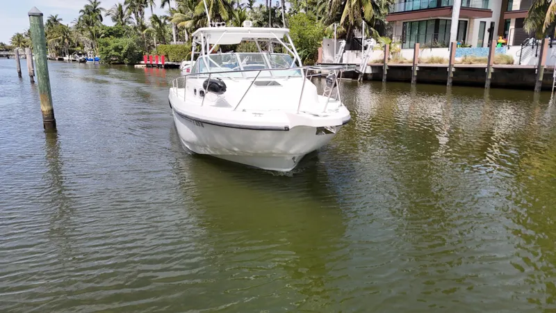 Slide: The Image of 1999 Boston Whaler 28 Conquest boat on a calm waterway near palm trees and docks. - 21