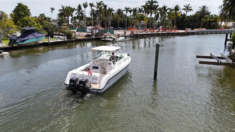 Slide: The Image of 1999 Boston Whaler 28 Conquest boat cruising on a calm waterway with palm trees. - 22