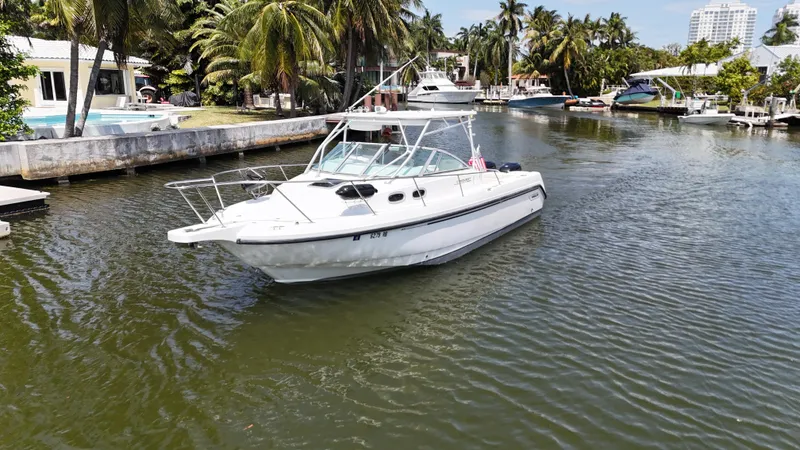 Slide: The Image of 1999 Boston Whaler 28 Conquest boat on a scenic canal with palm trees. - 23