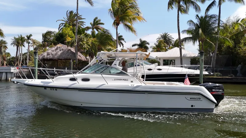 Slide: The Image of 1999 Boston Whaler 28 Conquest boat cruising on a tropical waterway with palm trees. - 24