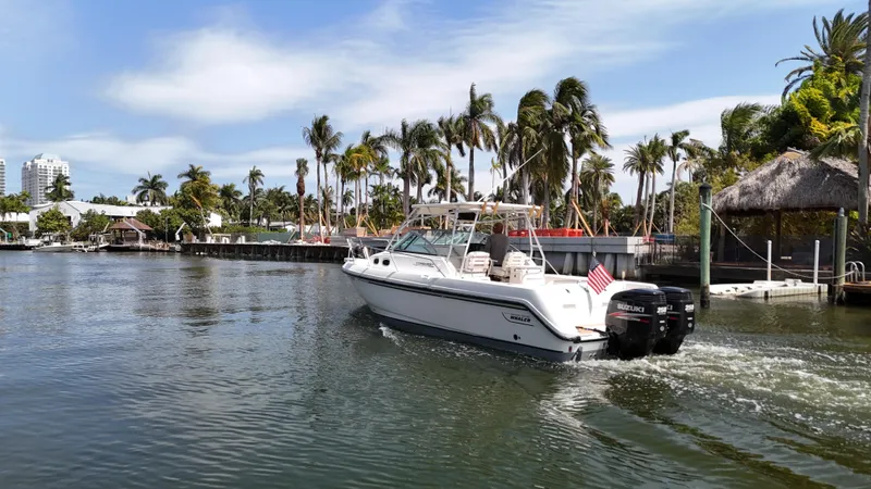 Slide: The Image of 1999 Boston Whaler 28 Conquest cruising on a tropical waterway with palm trees. - 25