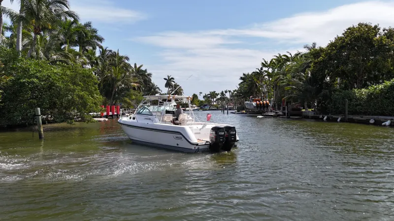 Slide: The Image of 1999 Boston Whaler 28 Conquest boat cruising through a scenic, tropical waterway. - 30