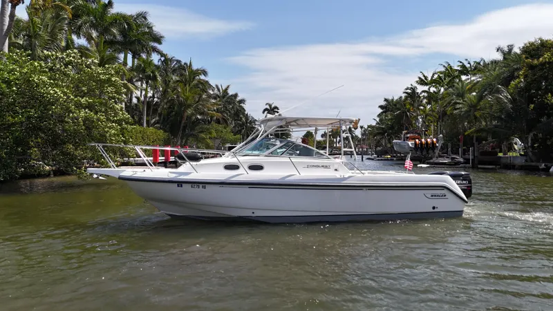 Slide: The Image of 1999 Boston Whaler 28 Conquest boat cruising on a scenic waterway with lush greenery. - 31