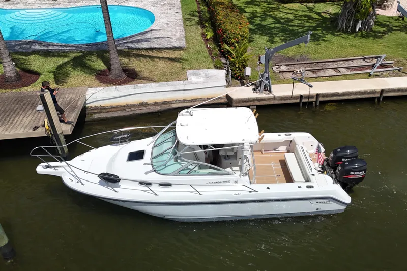 Slide: The Image of 1999 Boston Whaler 28 Conquest boat docked near a poolside area. - 34