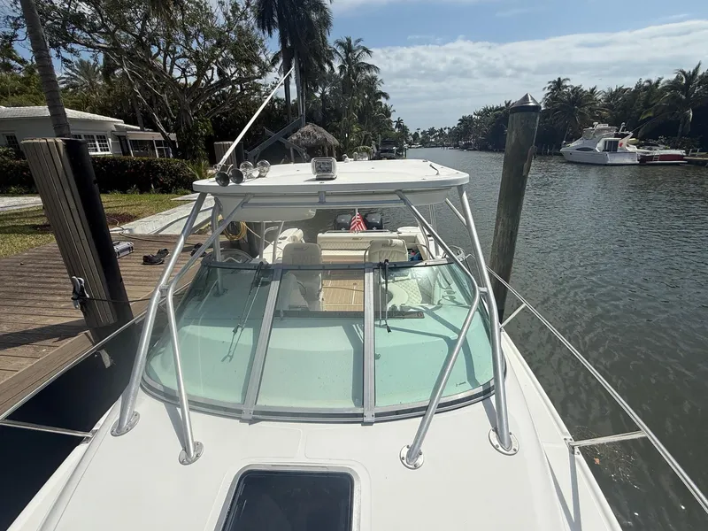 Slide: The Image of 1999 Boston Whaler 28 Conquest docked by a scenic canal with palm trees. - 4