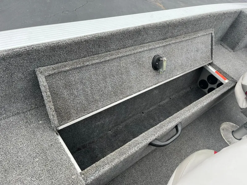 Slide: The Image of 2010 Alumacraft Navigator 175 CS boat storage compartment with gray interior and secure latch. - 19