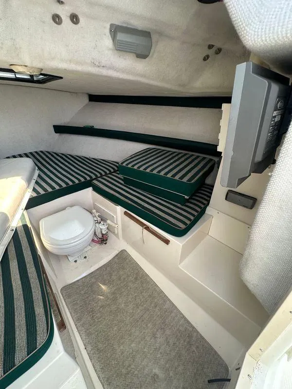 Slide: The Image of 1998 Pursuit 2460 Denali cabin interior with striped cushions and compact amenities. - 10