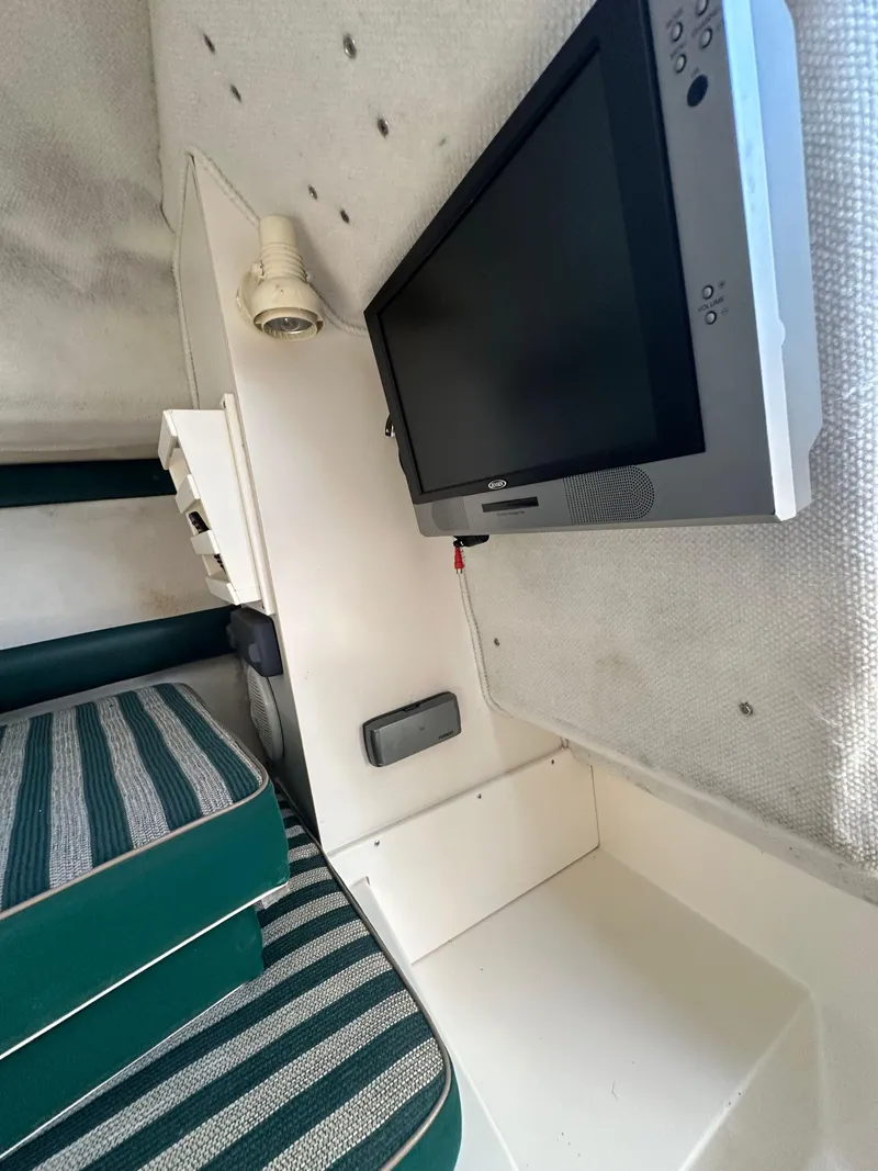 Slide: The Image of Interior of a 1998 Pursuit 2460 Denali boat with striped seating and mounted TV. - 12