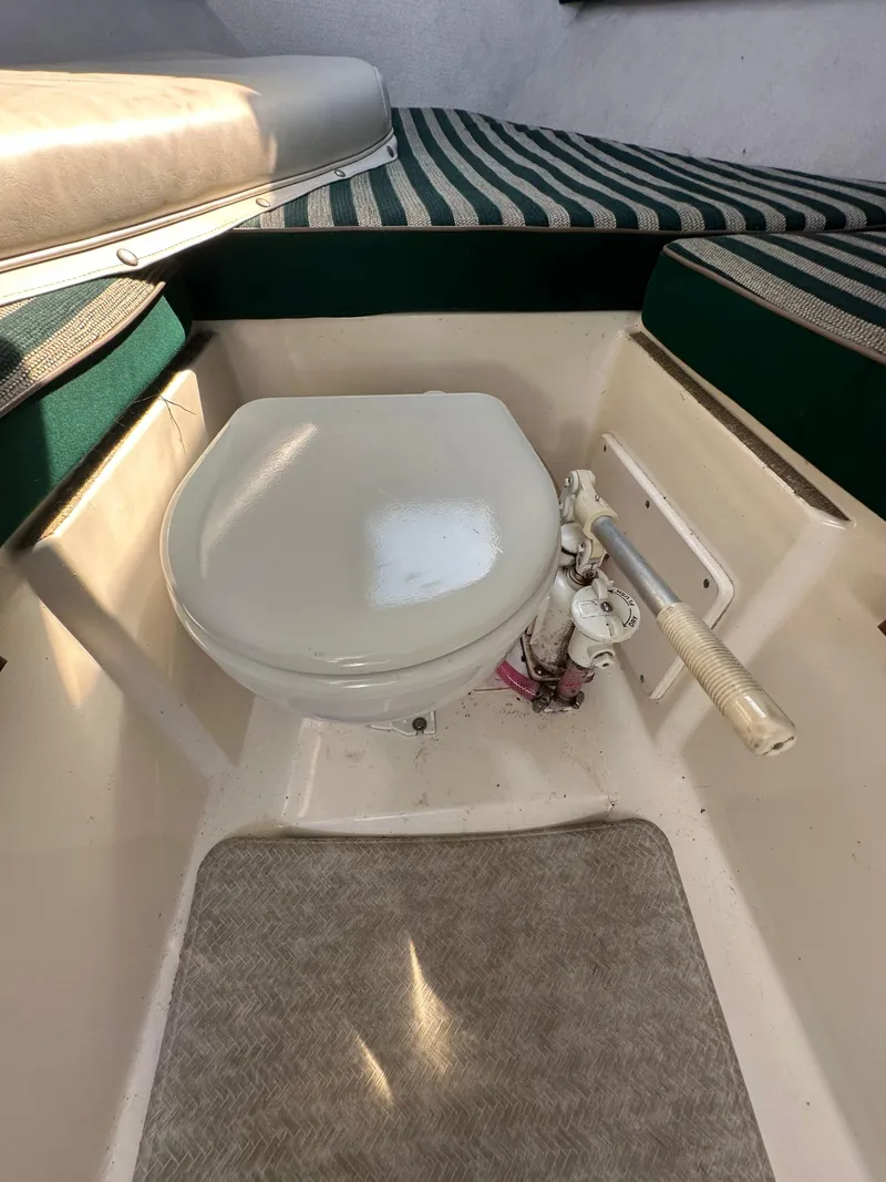 Slide: The Image of 1998 Pursuit 2460 Denali boat interior with toilet and striped seating. - 13