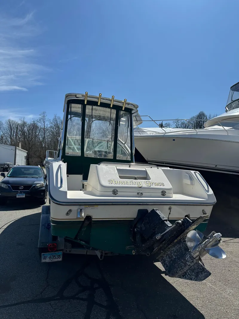 Slide: The Image of 1998 Pursuit 2460 Denali boat, rear view, parked outdoors under clear blue sky. - 14