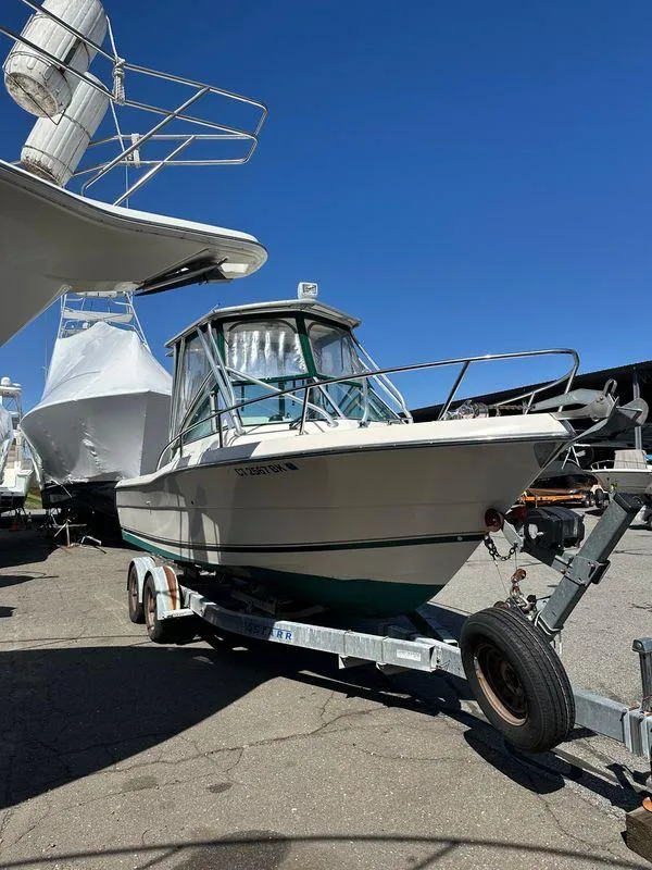 Slide: The Image of 1998 Pursuit 2460 Denali boat on trailer, parked outdoors under clear blue sky. - 2