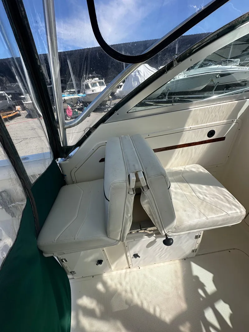 Slide: The Image of 1998 Pursuit 2460 Denali boat interior with white seating and clear canopy. - 4