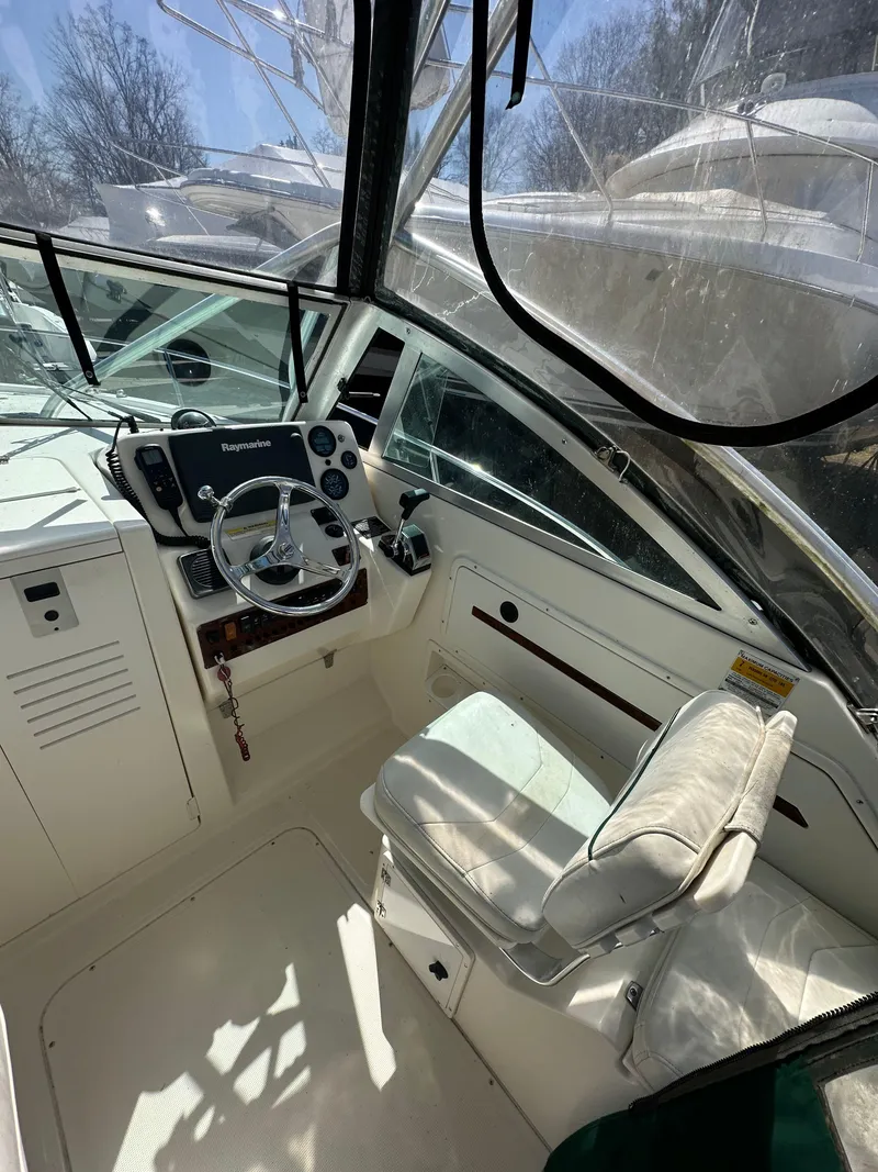 Slide: The Image of 1998 Pursuit 2460 Denali boat interior with steering wheel and cushioned seat. - 5