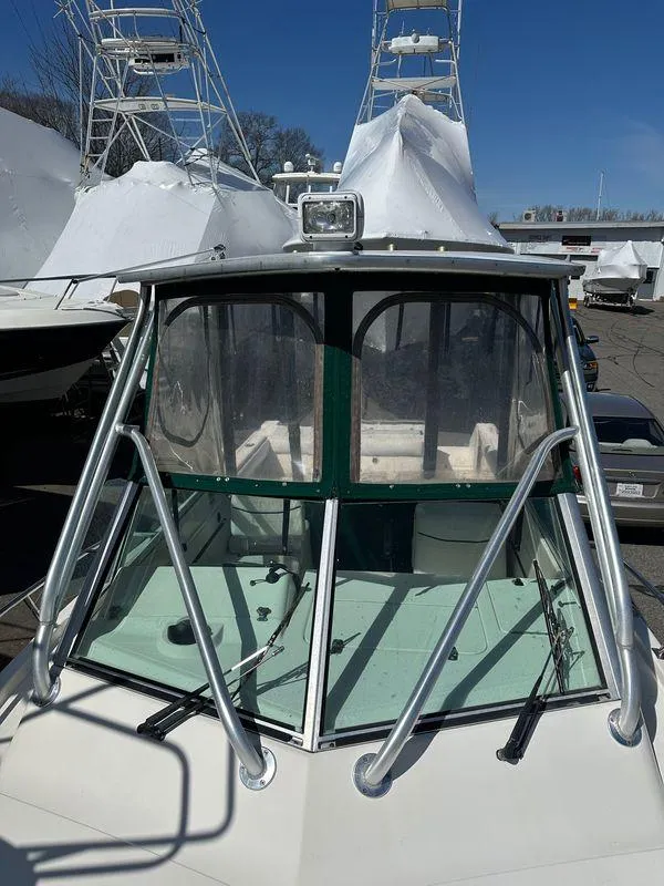 Slide: The Image of 1998 Pursuit 2460 Denali boat with enclosed cabin and metal railings, docked outdoors. - 9