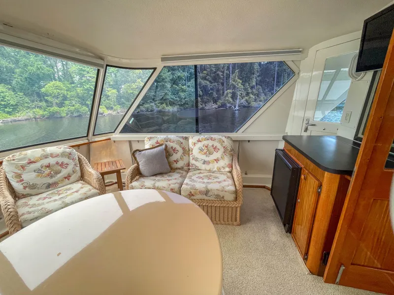 Slide: The Image of Interior of 1984 Hatteras 53 Motoryacht with wicker seating, large windows, and scenic water view. - 17