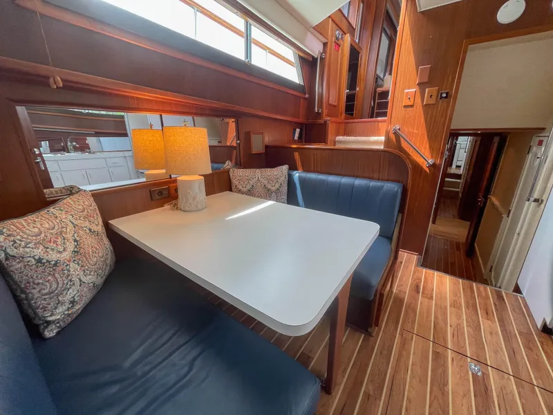 Slide: The Image of Interior of 1984 Hatteras 53 Motoryacht with dining area, blue seating, and wooden flooring. - 20