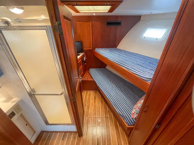 Slide: The Image of 1984 Hatteras 53 Motoryacht cabin with wooden interior, bunk beds, and adjacent bathroom. - 26