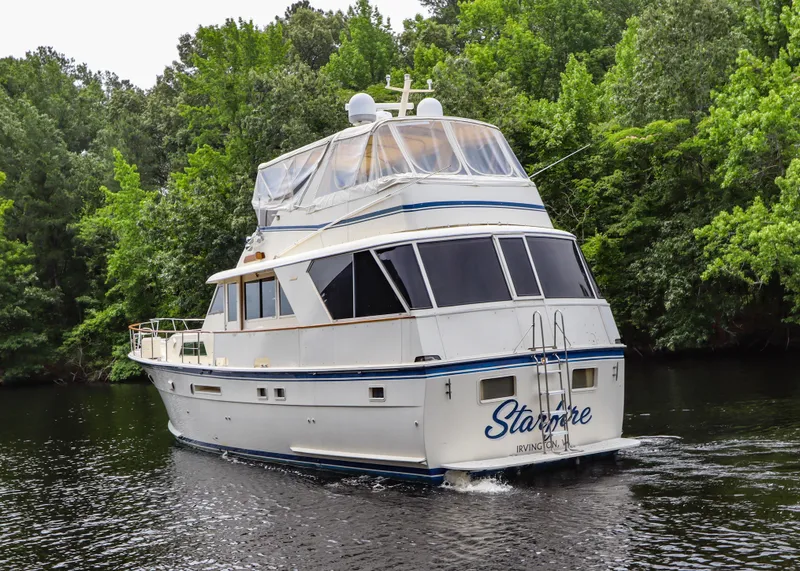 Slide: The Image of 1984 Hatteras 53 Motoryacht cruising on a serene river, surrounded by lush greenery. - 3