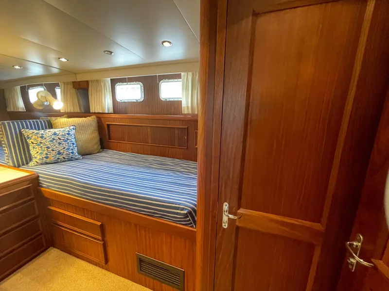 Slide: The Image of 1984 Hatteras 53 Motoryacht cabin with striped bedding and wooden interior. - 33