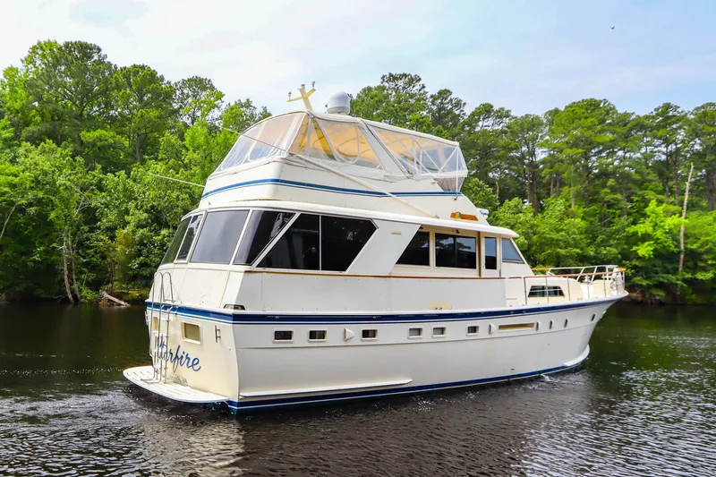 Slide: The Image of 1984 Hatteras 53 Motoryacht cruising on a serene river with lush green trees. - 4
