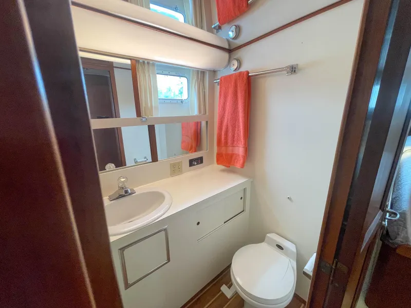 Slide: The Image of 1984 Hatteras 53 Motoryacht bathroom with sink, toilet, mirror, and orange towel. - 41