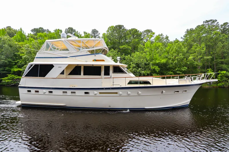 Slide: The Image of 1984 Hatteras 53 Motoryacht cruising on a serene river, surrounded by lush greenery. - 5