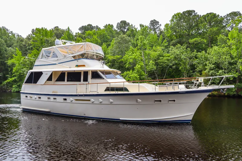 Slide: The Image of 1984 Hatteras 53 Motoryacht cruising on a serene river, surrounded by lush greenery. - 6