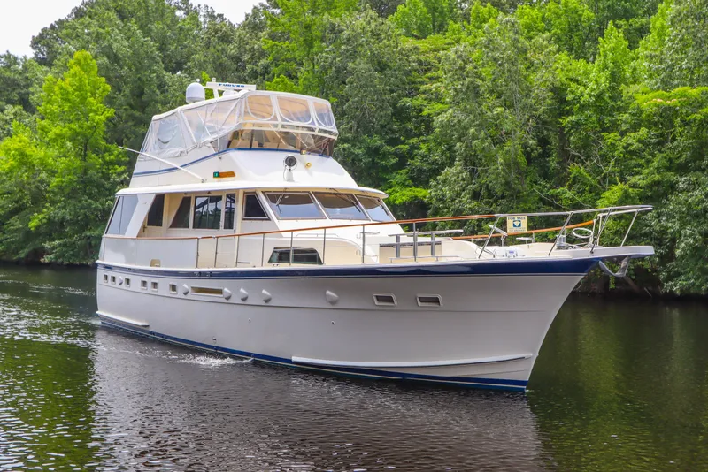 Slide: The Image of 1984 Hatteras 53 Motoryacht cruising on a serene river, surrounded by lush greenery. - 7