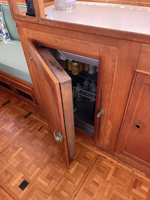 Slide: The Image of Wooden cabinet with open door revealing a mini fridge inside a 1981 Grand Banks 36 Classic boat. - 19