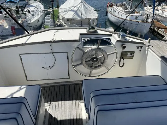 Slide: The Image of 1981 Grand Banks 36 Classic yacht helm with steering wheel and controls, docked at marina. - 43