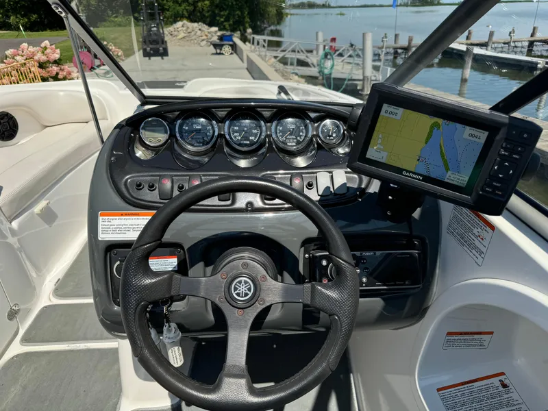 Slide: The Image of 2006 Yamaha Boats AR 210 dashboard with steering wheel and navigation system by the water. - 10
