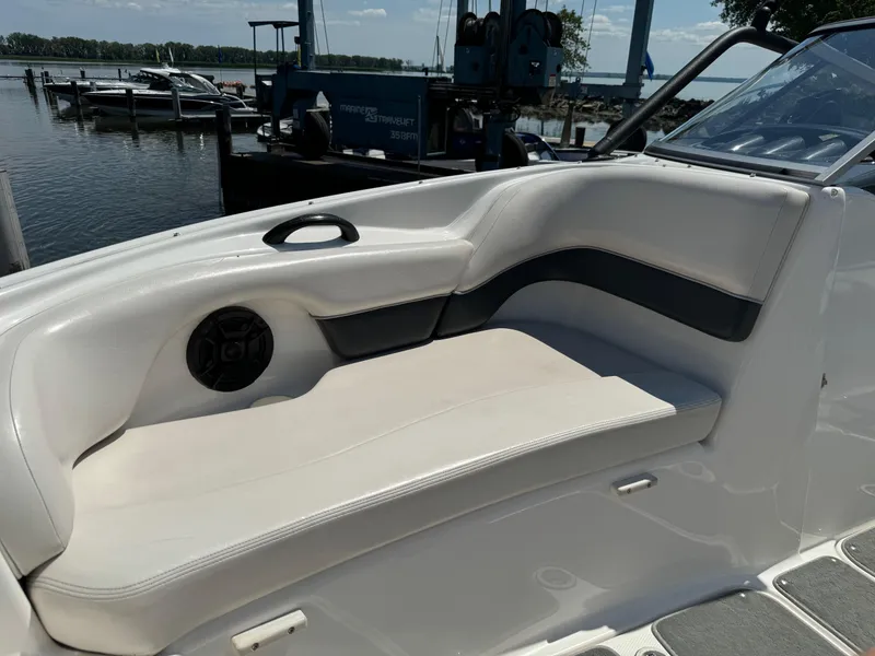 Slide: The Image of 2006 Yamaha AR 210 boat interior with white seating and speaker, docked by the water. - 16