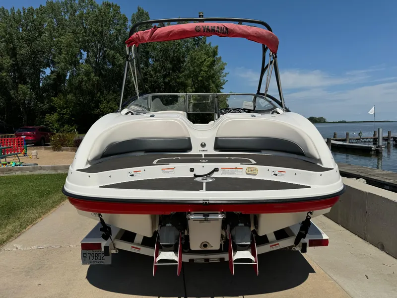 Slide: The Image of 2006 Yamaha Boats AR 210 on trailer by lakeside, featuring red canopy and dual engines. - 2