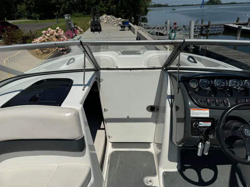 Slide: The Image of 2006 Yamaha Boats AR 210 interior with dashboard and seating, docked by a scenic lake. - 21